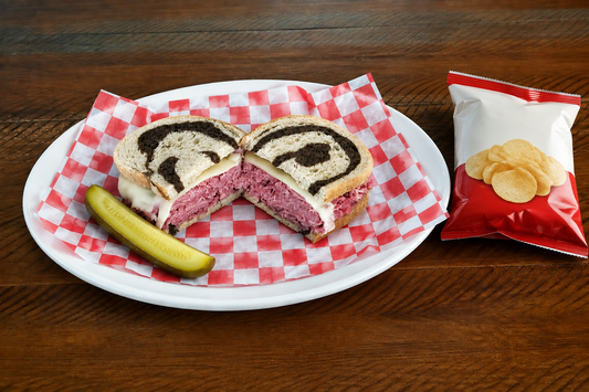 Deli sandwich with a pickle and bag of chips